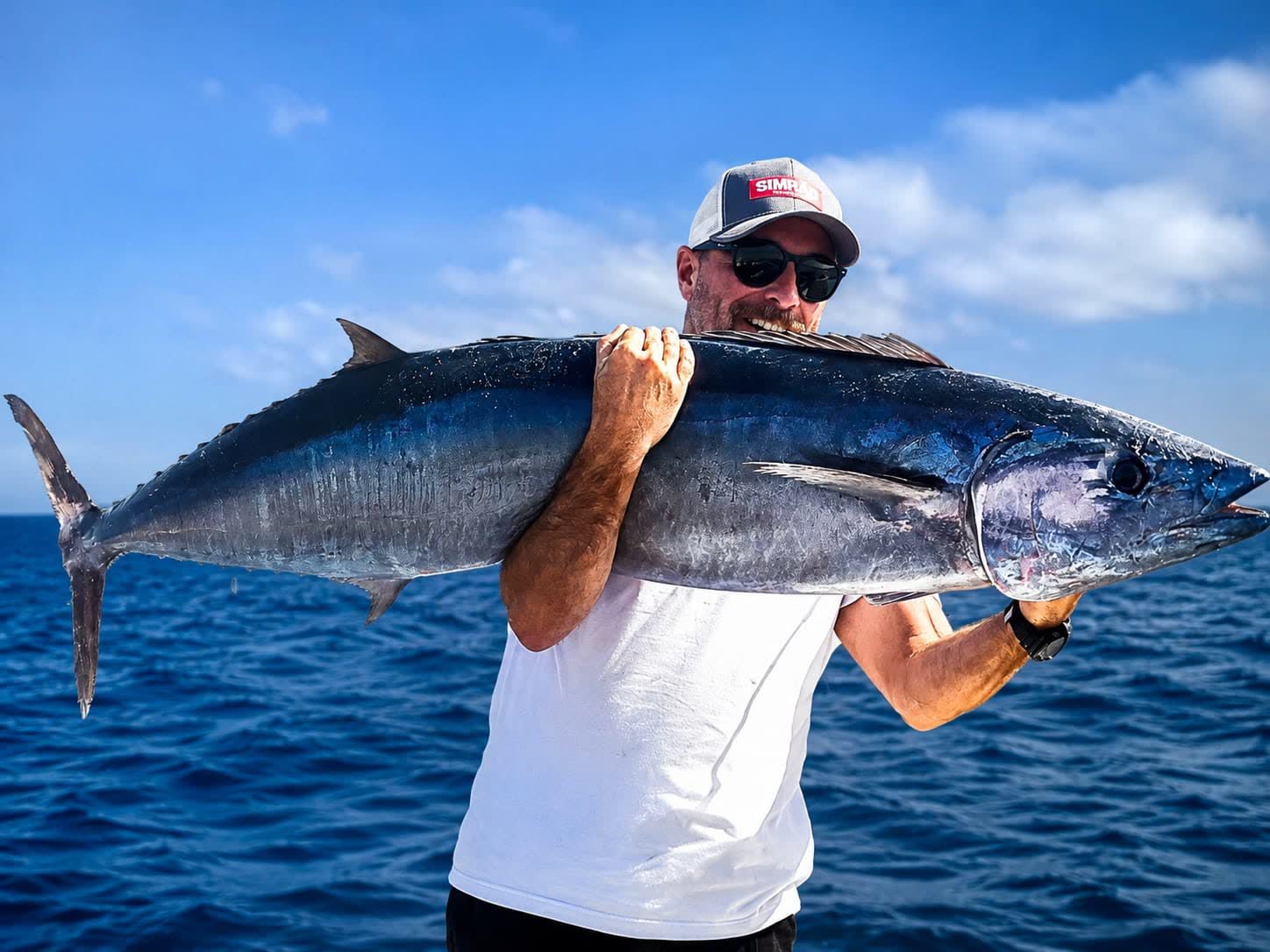 Wahoo alongside the boat in blue water, the lure still in its mouth